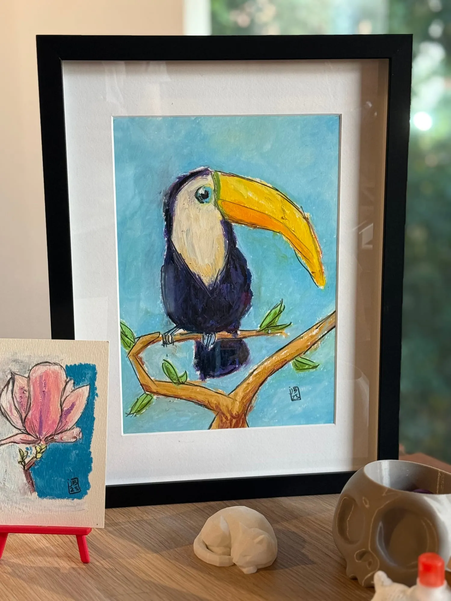 Tucán — el cuadro ya enmarcado, junto a una magnolia pequeña