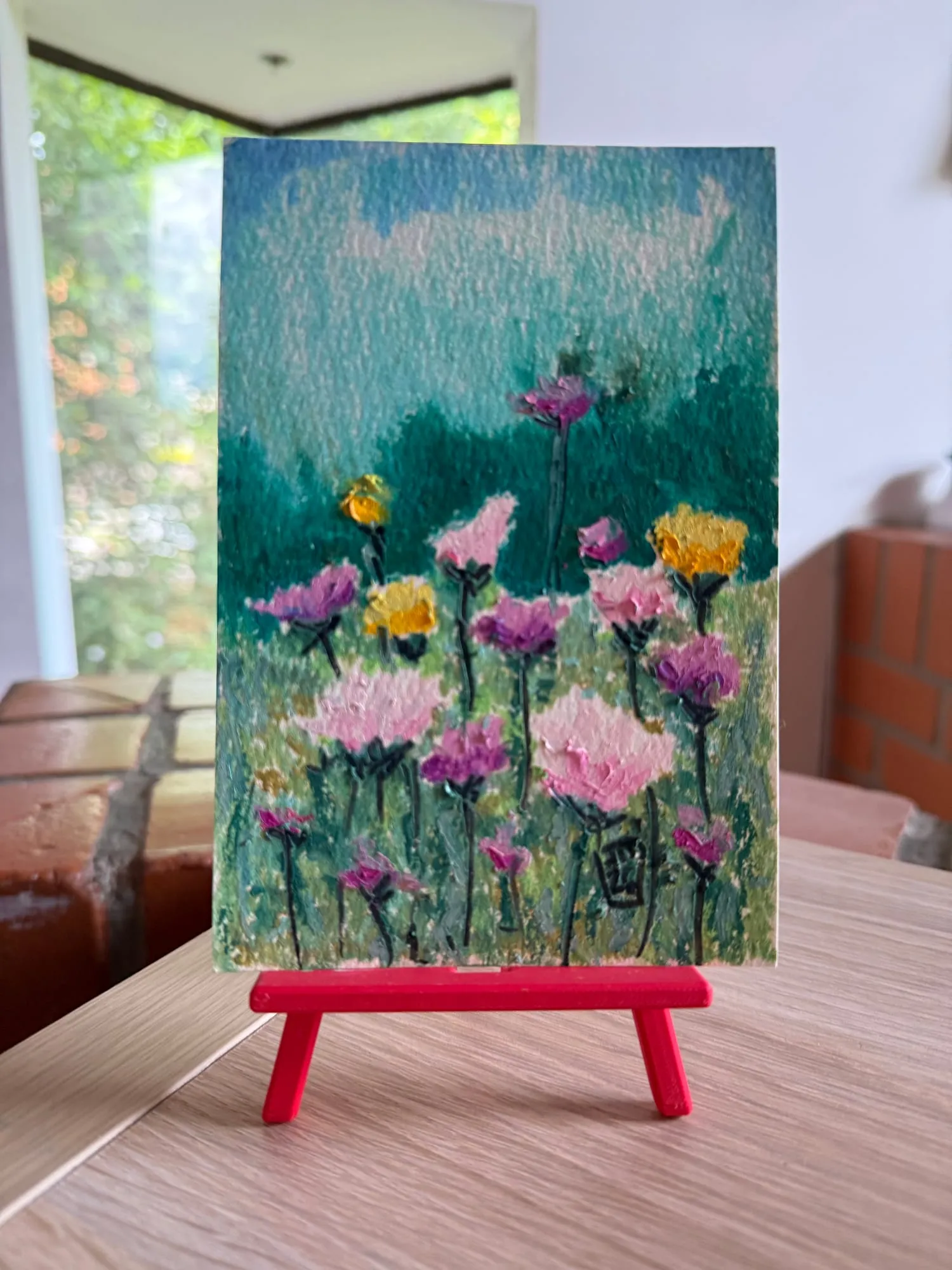 Campo de flores rosadas, moradas y amarillas sobre verde, óleo pastel